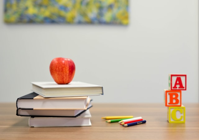 Image of an apple sitting on a stack of books.